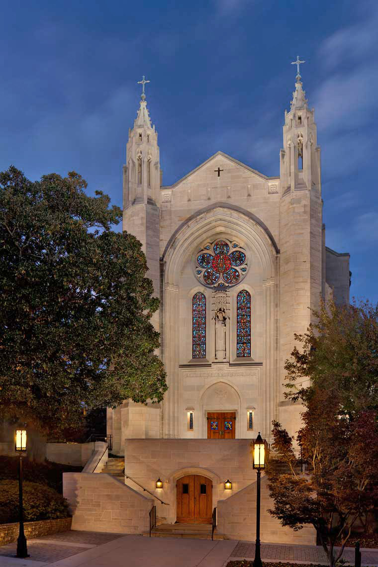 A twilight view of the exterior entrance to the Cathedral of Christ the King, with illuminated stained glass