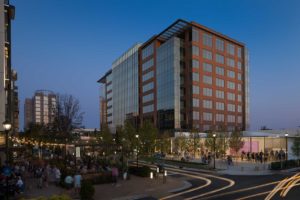 A twilight exterior view of the architecture at 8000 Avalon Building and its surrounding shops