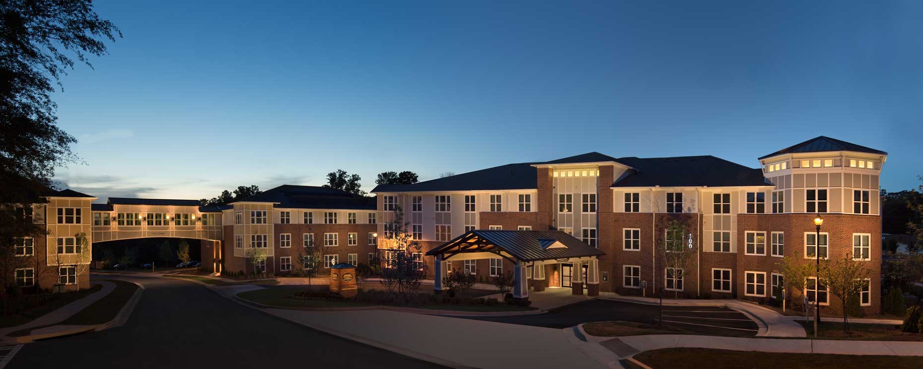 A stunning twilight view of the buildings and bridge at the Columbia Brookside Senior Residences