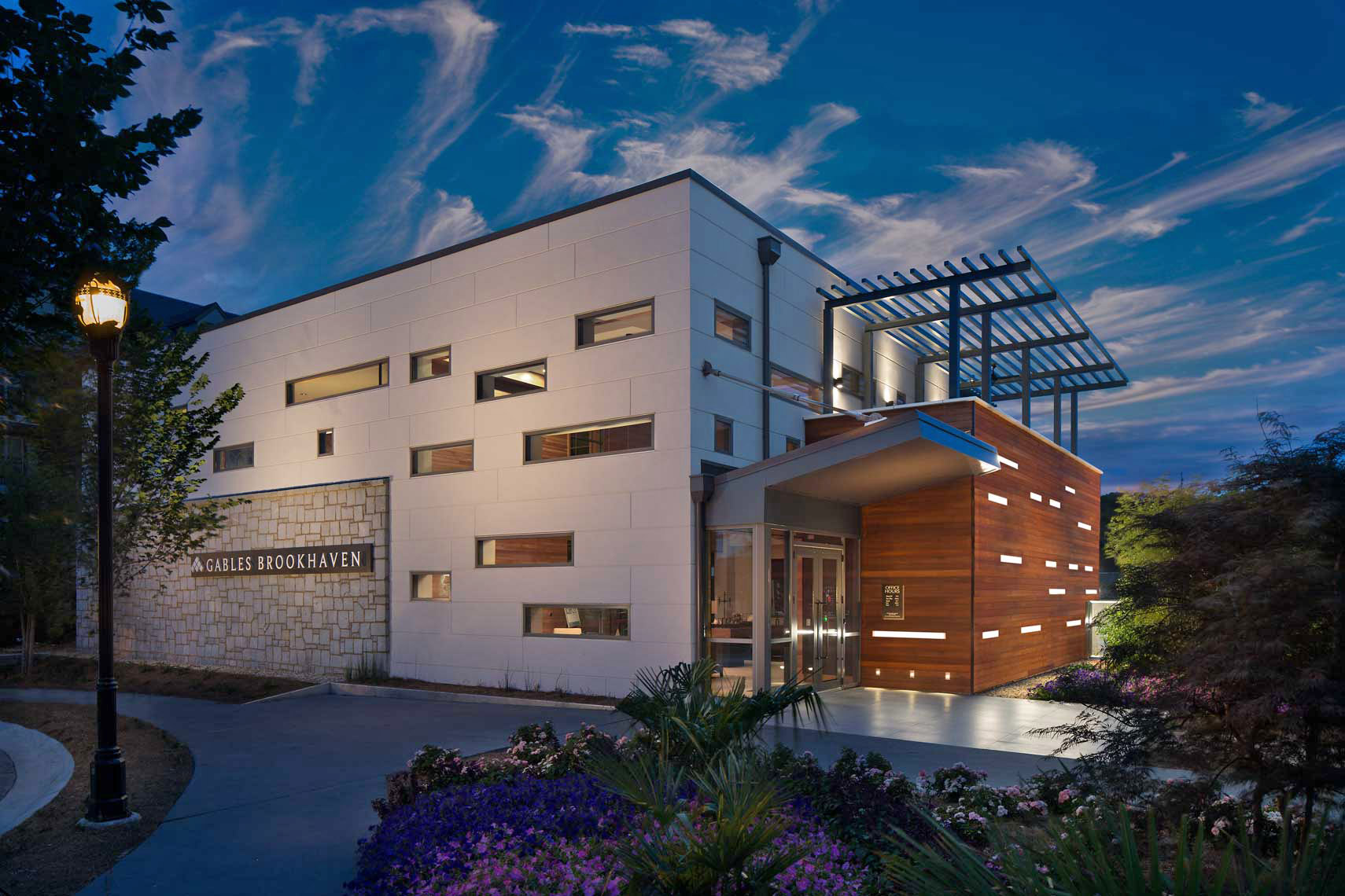 An exterior twilight view of the Gables Brookhaven Leasing Office, showing bold design and lighting