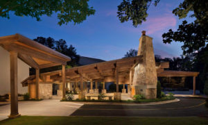 A lighted exterior view of a wood and stone outdoor pavilion against a twilight sky