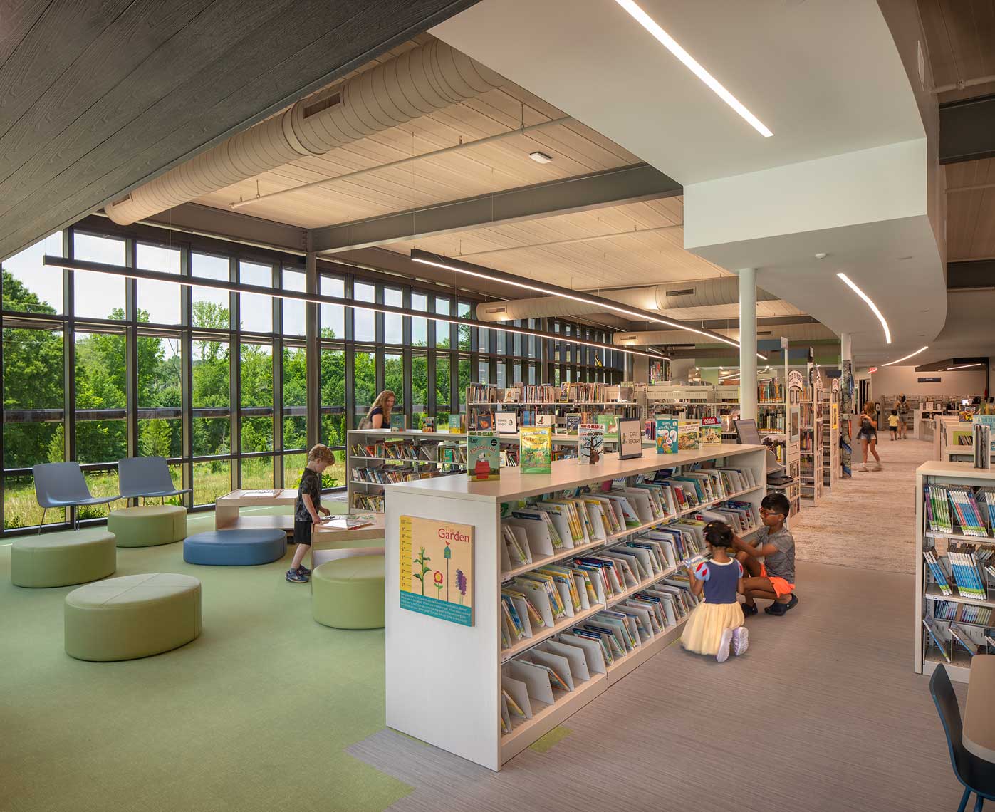 A view of the Children's Area of the Denmark Branch Library, with children choosing books from the stacks