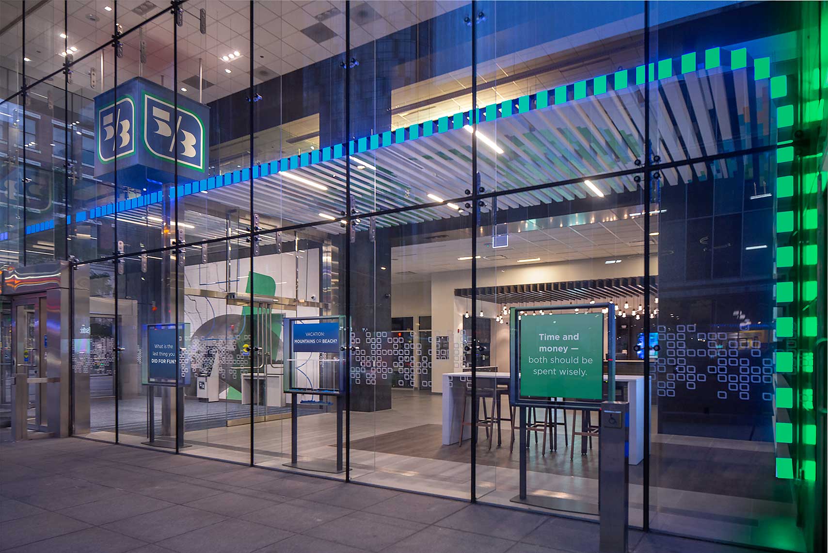 A night view looking into the Fifth Third Bank in downtown Chicago with colorful graphics and bright signage seen through the two-story glass.