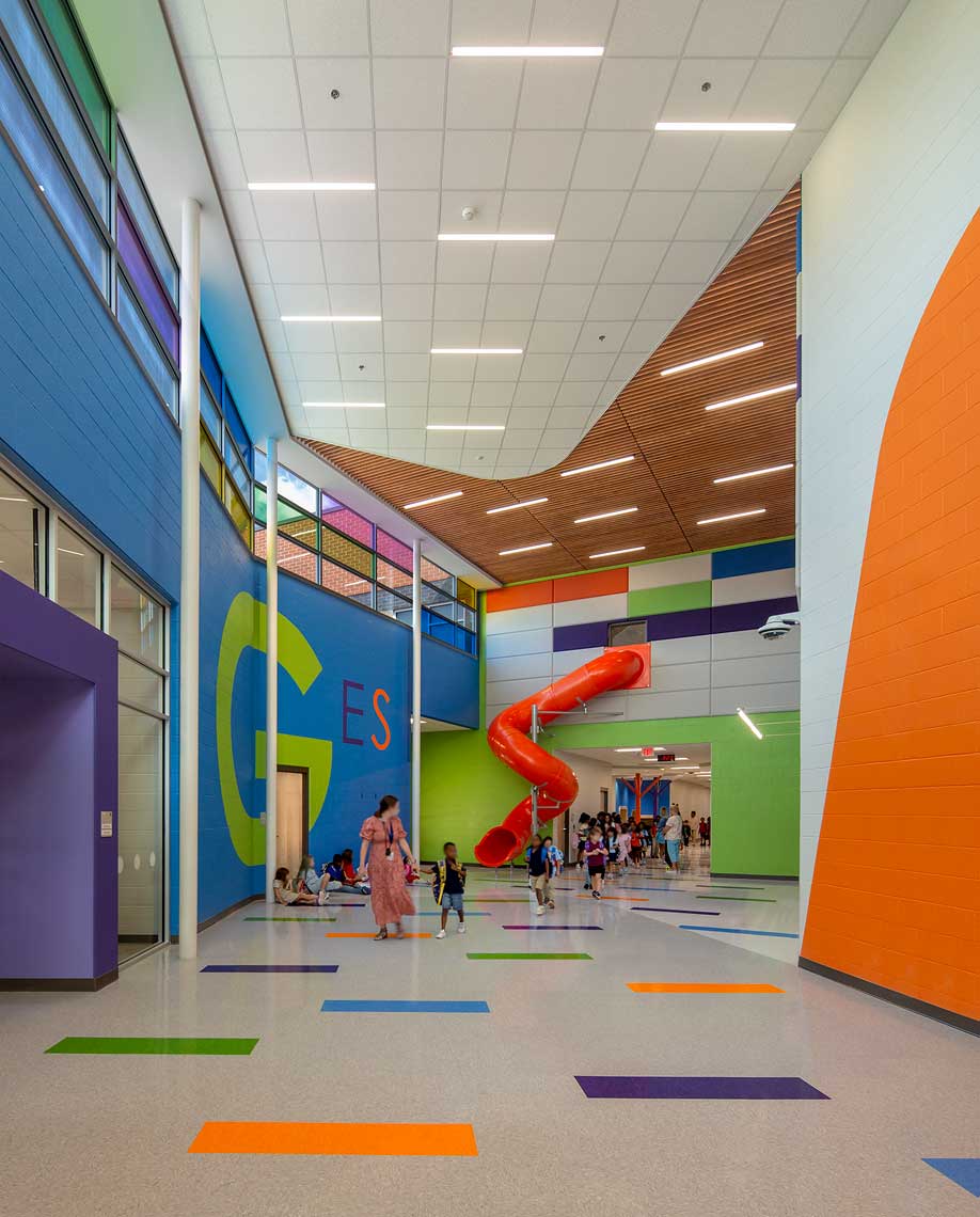 A vertical view showing the main hallway of Goodlettsville Elementary School, featuring the bright orange two-story slide from the second floor to the first