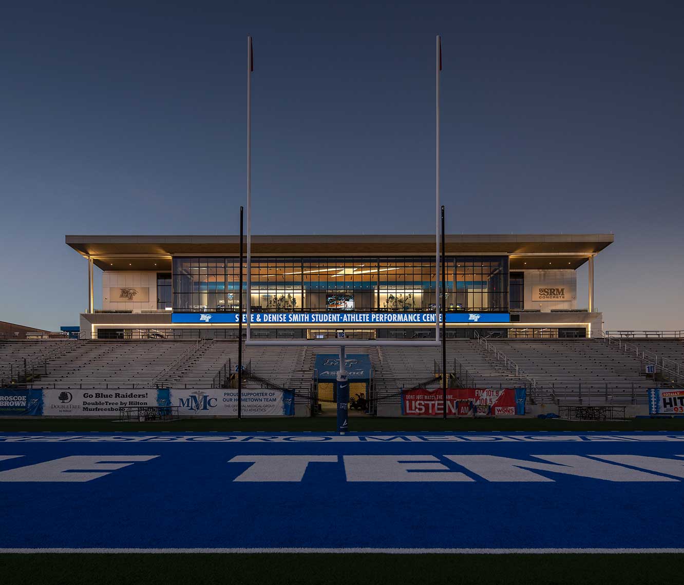 A twilight view of the MTSU Student-Athlete Performance Center from the field, showing the custom lightning bolt in the ceiling of the Club Lounge