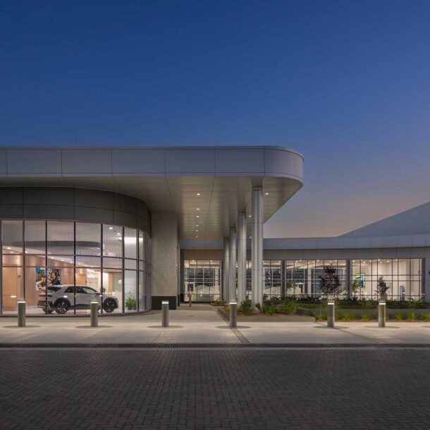 An eye level view at twilight of the Quick Start - Hyundai Mobility Training Center of Georgia by SSOE Group, showing a Hyundai car parked inside the lobby