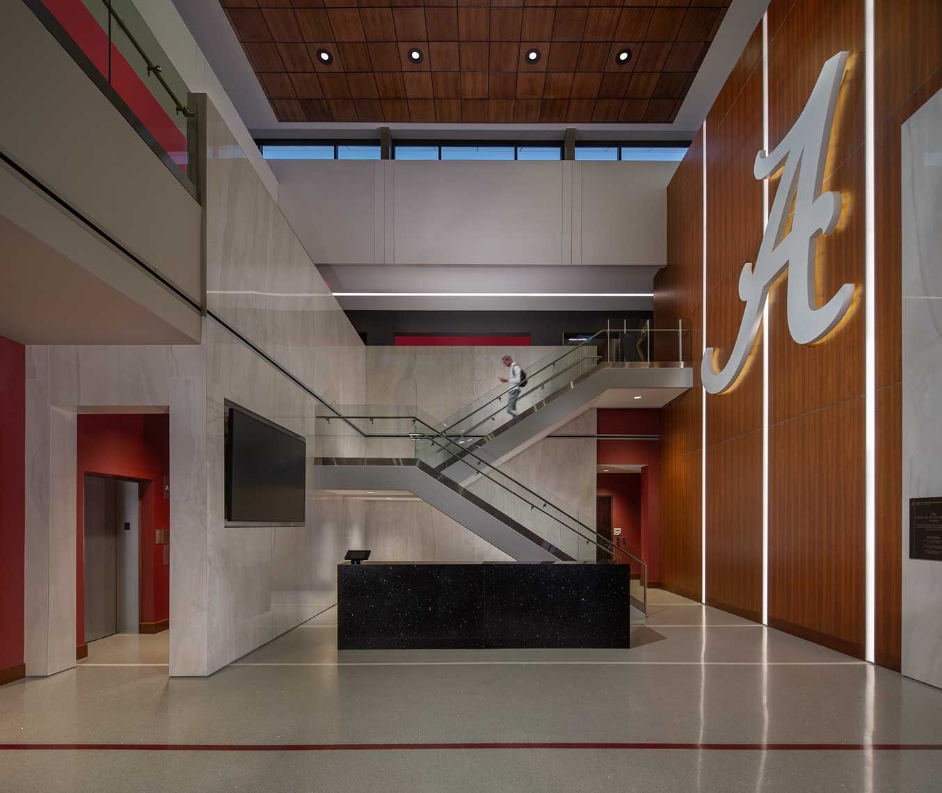 A student athlete descends the stairs in the striking University of Alabama Training Facility Lobby