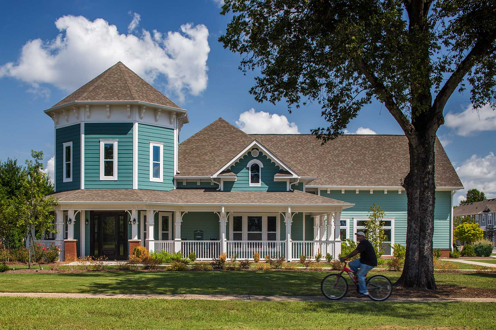 A view showing a cyclist riding past the charming Columbus Commons Leasing and Amenities Center